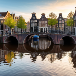 A beautiful, cinematic shot of an Amsterdam canal. Traditional Dutch gable houses with intricate facades line the water's edge, their reflections shimmering in the calm canal. Several classic Dutch bicycles are neatly parked along the canal path. A historic brick bridge gracefully arches over the water in the mid-ground. The sky is a soft, atmospheric mix of light blues and subtle clouds, casting a gentle, diffused light. The scene is bathed in a warm, inviting glow, capturing the essence of a serene spring afternoon. Shot on a Canon EOS R5, f/8, ISO 100, golden hour lighting, highly detailed, photorealistic.